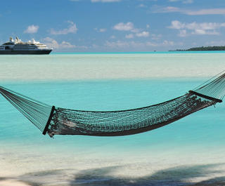 tropical island hammock with cruise ship behind