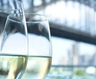 Close up of two glasses of wine with Sydney Harbour Bridge in the background