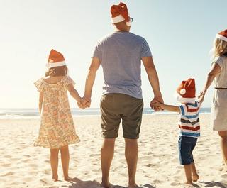 Shot of a family of four walking on the beach on Christmas. Photo: Getty Images.