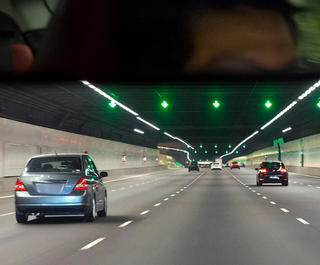 A view of cars driving through a tunnel from the point of view of a driver of the car at the rear