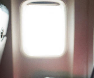 A row of seats on an airplane with sunlight coming in from the window
