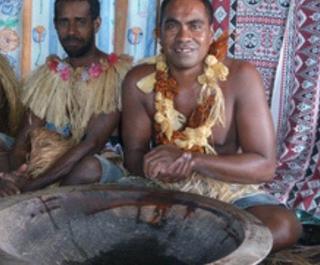 Fijian men sitting on straw mat with bowl of kava in front 