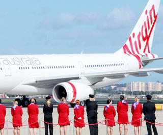 Virgin Crew standing on the runway on a red carpet looking at one of Virgin Australia's planes