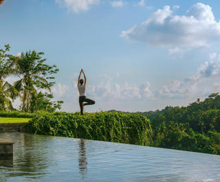 A woman performs yoga by a pool at Mandapa Ritz Carlton Ubud in Bali.