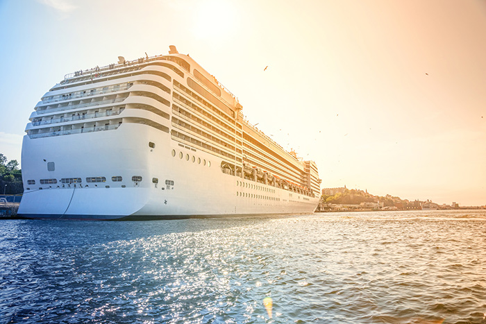 a cruise ship towers over a town while docked in port